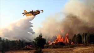 wildfire insurance Costa del Sol. Wildfire in Spain with firefighting plane over dry countryside