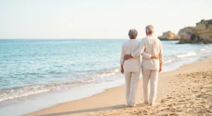a retired couple enjoying retirement walking on a beach in Spain